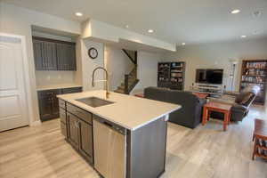 Kitchen featuring a center island with sink, sink, stainless steel dishwasher, and light hardwood / wood-style floors