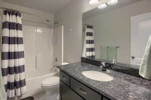 Full bathroom with tile patterned floors, vanity, toilet, and shower / bath combo with shower curtain