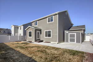 Back of property with a shed, a patio area, and a lawn