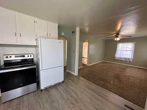 Kitchen with stainless steel range with electric stovetop, light hardwood / wood-style flooring, white fridge, ceiling fan, and white cabinets