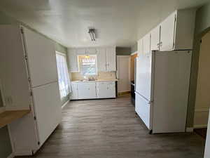 Kitchen with white refrigerator, white cabinetry, decorative backsplash, and light wood-type flooring