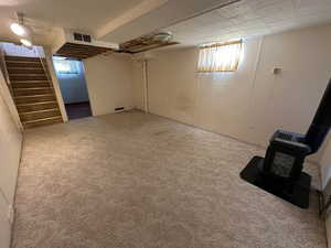 Basement with carpet and a wood stove