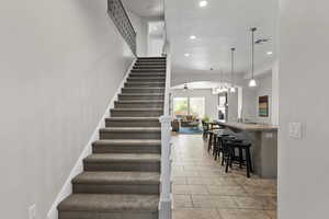 Stairway with tile patterned flooring, recessed lighting, ceiling fan, arched walkways, and a textured ceiling