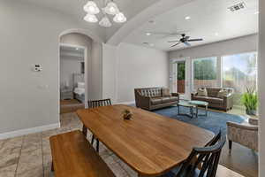 Dining area with arched walkways, ceiling fan, recessed lighting, a chandelier, and a textured ceiling