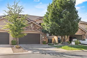 Obstructed view of property with stucco siding, stone siding, driveway, and a tiled roof