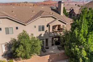 Rear view of house with a balcony, a mountain view, stucco siding, a chimney, and a patio area