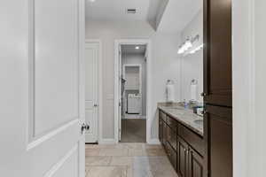 Full bath featuring double vanity, washer / dryer, and tile patterned floors