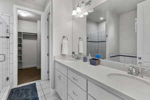 Bathroom featuring a stall shower, a walk in closet, double vanity, and tile patterned flooring