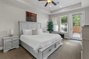 Carpeted bedroom featuring access to exterior, a raised ceiling, recessed lighting, and ceiling fan