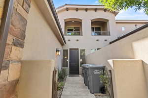 Entrance to property with stucco siding and a balcony