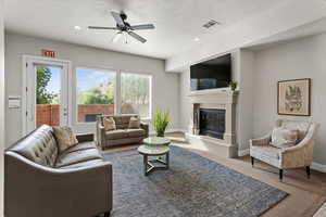 Living area with a glass covered fireplace, recessed lighting, a textured ceiling, carpet floors, and a ceiling fan