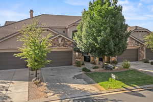 View of front of house featuring stone siding, stucco siding, concrete driveway, and a tiled roof