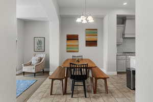 Dining area with a chandelier, light tile patterned flooring, and recessed lighting