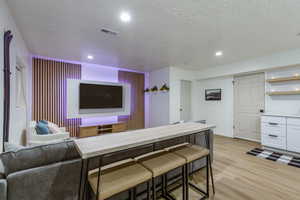 Cinema room with light hardwood / wood-style floors and a textured ceiling