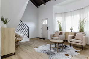 Entryway featuring beamed ceiling, high vaulted ceiling, and light hardwood / wood-style flooring