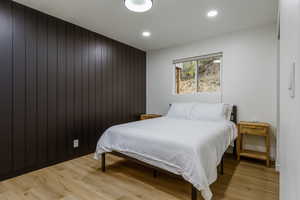 Bedroom with wooden walls and light wood-type flooring