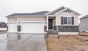 Craftsman inspired home featuring driveway, an attached garage, a shingled roof, stone siding, and board and batten siding