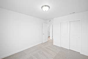 Unfurnished bedroom featuring light carpet and a closet