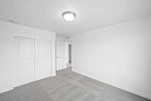 Unfurnished bedroom featuring light carpet and a closet