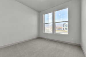 Spare room featuring light colored carpet and vaulted ceiling