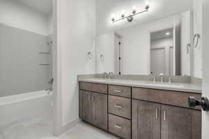 Bathroom with tiled shower / bath, tile patterned floors, and vanity