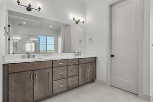 Bathroom with a tile shower, vanity, and tile patterned flooring