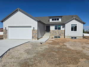 View of front facade featuring stone siding, an attached garage, board and batten siding, driveway, and roof with shingles