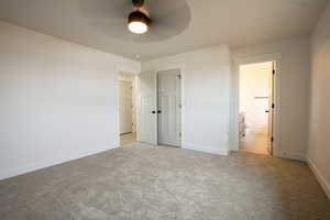 Unfurnished bedroom featuring light colored carpet, ceiling fan, and ensuite bathroom