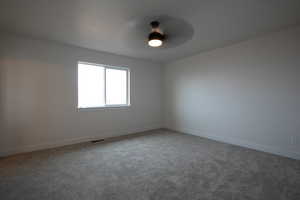 Carpeted empty room with ceiling fan