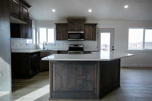 Kitchen with dark brown cabinetry, sink, stainless steel appliances, and a kitchen island