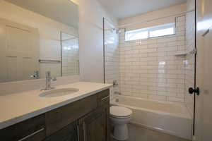 Full bathroom with tiled shower / bath combo, vanity, tile patterned floors, and toilet