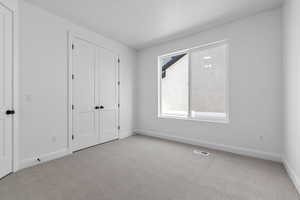 Unfurnished bedroom featuring light colored carpet and a closet