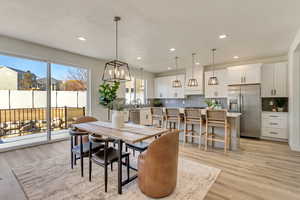 Dining room featuring sink, a textured ceiling, an inviting chandelier, and light hardwood / wood-style flooring