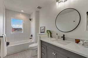 Full bathroom featuring tiled shower / bath, vanity, toilet, and wood-type flooring