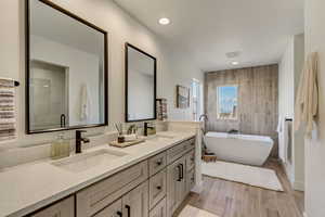 Bathroom featuring vanity, a bath, and tile walls