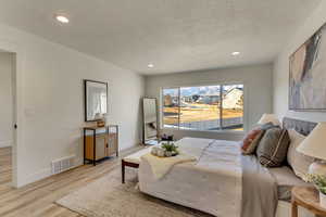 Bedroom with light hardwood / wood-style floors and a textured ceiling