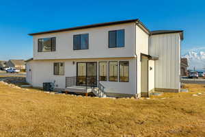 Rear view of house featuring central AC unit and a lawn