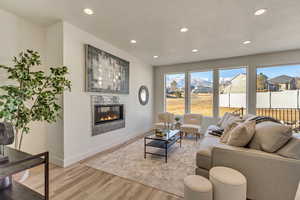 Living room with light hardwood / wood-style floors, a tile fireplace, and a textured ceiling