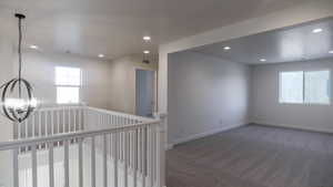 Spare room with dark colored carpet and a chandelier