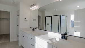 Bathroom with vanity, tile patterned flooring, and a shower with door