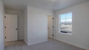 Unfurnished bedroom featuring light carpet and a mountain view