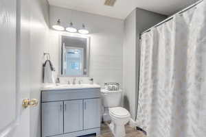 Hall bathroom featuring hardwood / wood-style flooring, vanity, and toilet and tub/shower