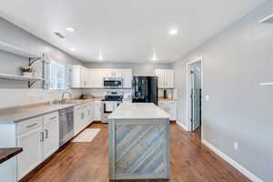 Kitchen featuring a kitchen island, white cabinetry, appliances with stainless steel finishes, and sink