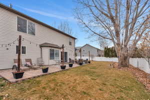 Rear view of property with a lawn and a patio