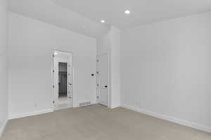 Carpeted spare room featuring vaulted ceiling