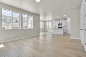 Unfurnished living room with an inviting chandelier and light hardwood / wood-style floors