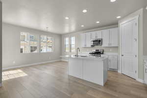 Kitchen with white cabinetry, sink, stainless steel appliances, and hanging light fixtures