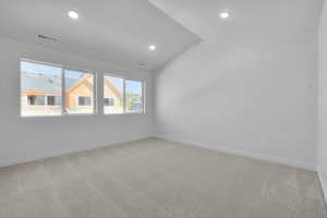 Empty room with lofted ceiling and carpet