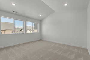 Spare room featuring light carpet, lofted ceiling, and a textured ceiling