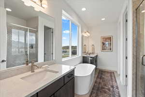 Bathroom featuring tile patterned floors, vanity, and shower with separate bathtub